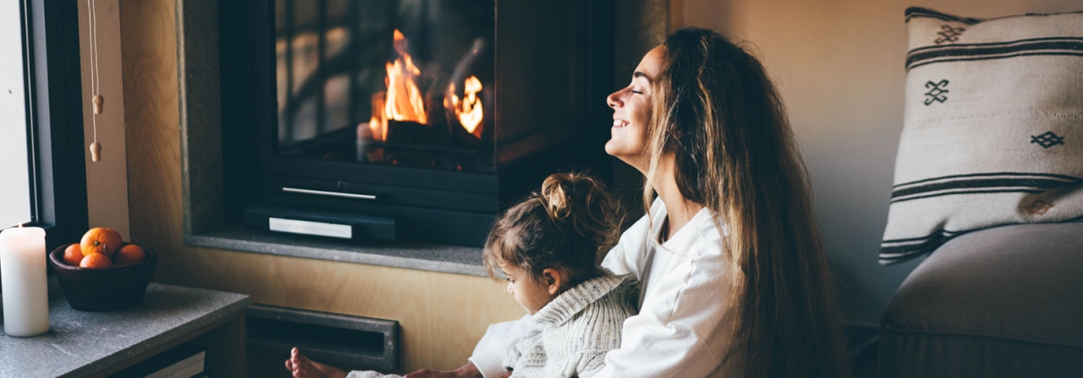 Woman sitting in front of a gas fireplace with her daughter in her lap.