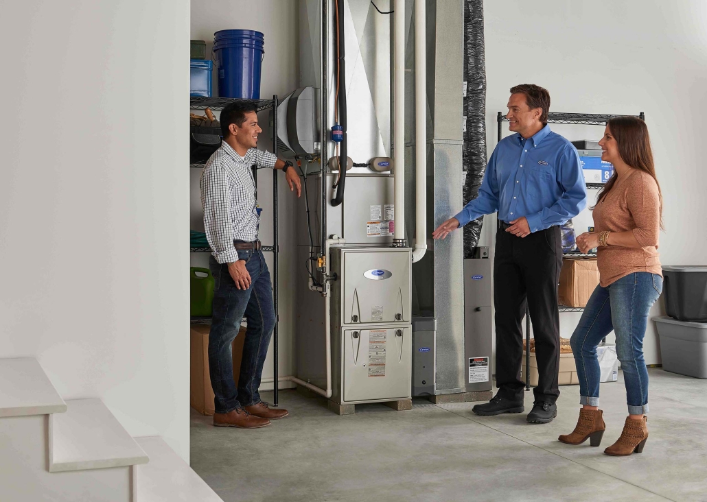 three people in basement looking at furnace