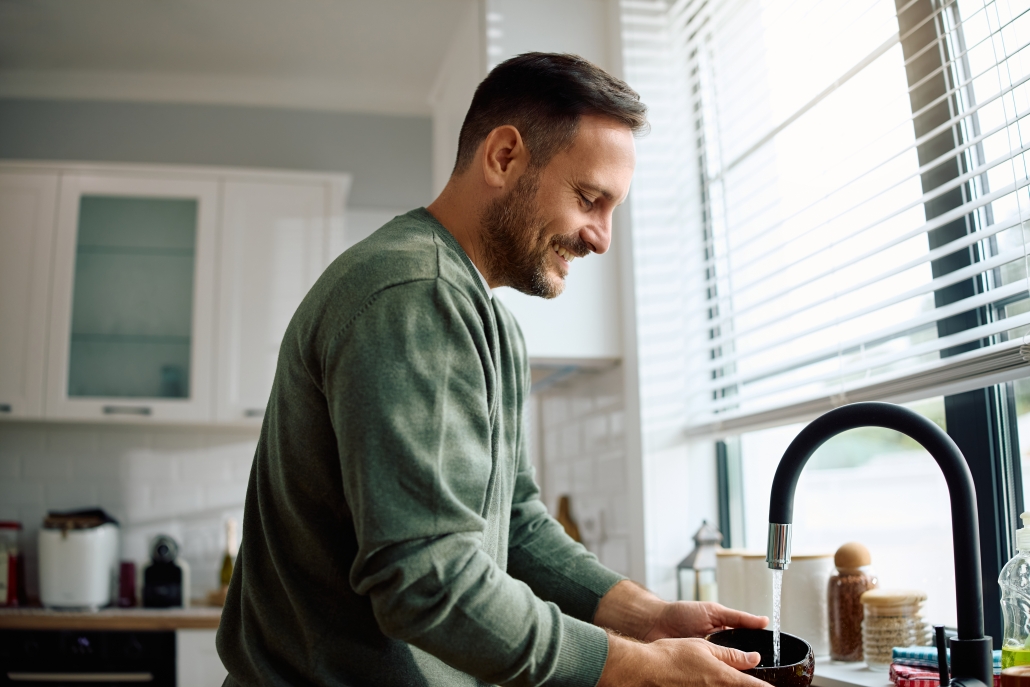 Happy mid adult man doing dishes at home. smiling man washing dishes in kitchen