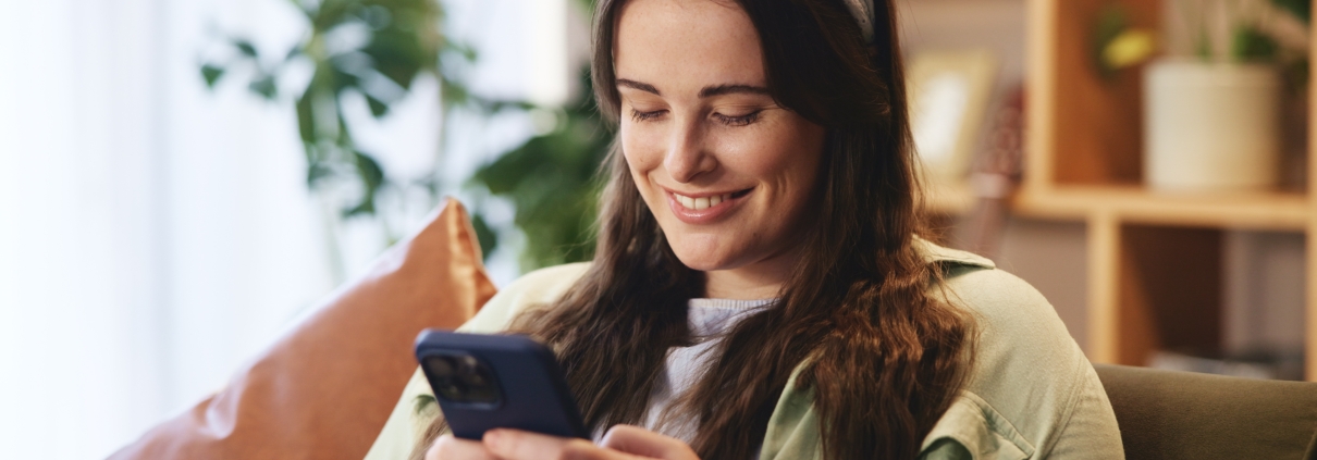 woman smiling at home looking at phone