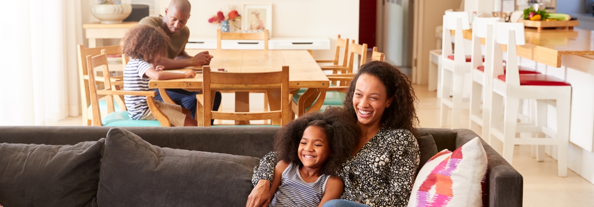 Mother And Daughter Sitting On Sofa At Home Watching Movie On TV Together