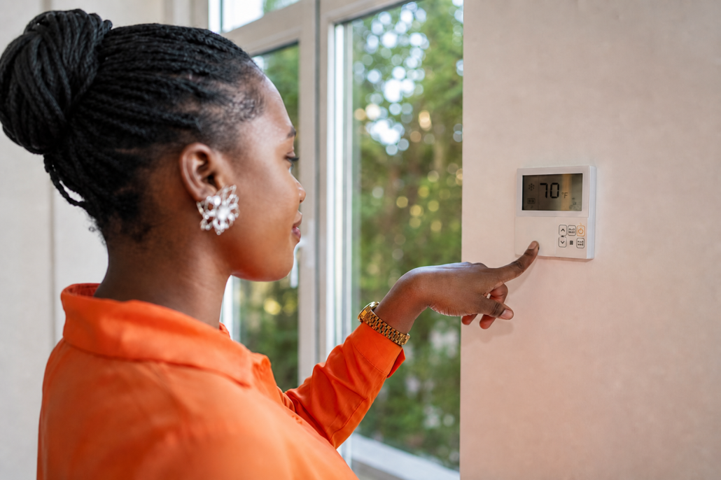 woman adjusting thermostat